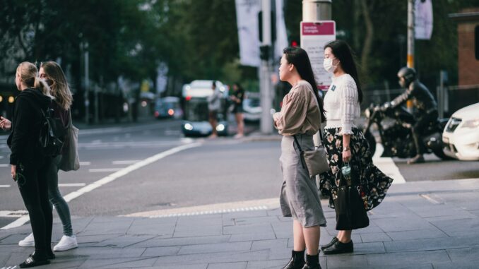 Photo by Kate Trifo woman in beige coat standing on sidewalk during daytime