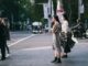 woman in beige coat standing on sidewalk during daytime