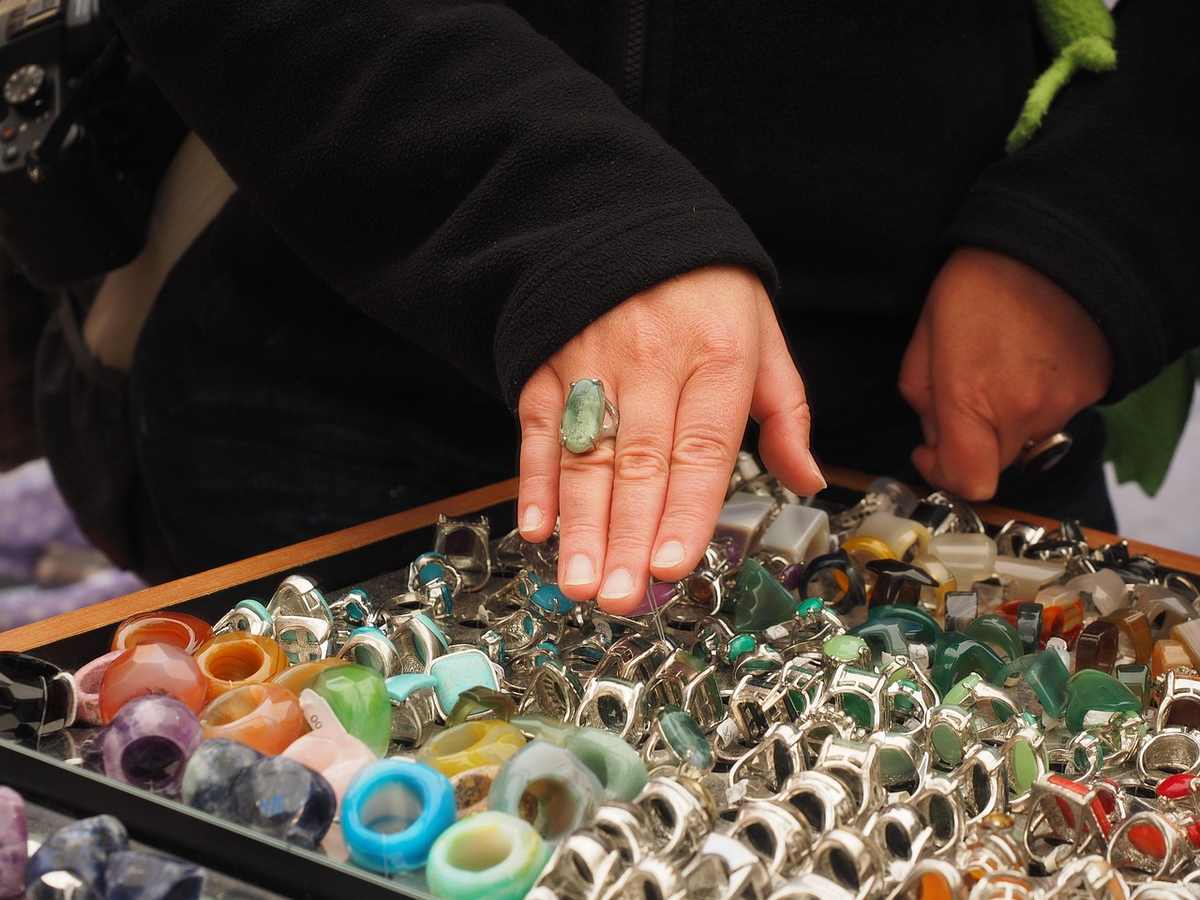 Une main choisit des bagues colorées parmi une collection de bijoux