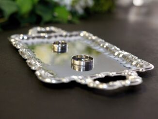 Un plateau en argent contenant deux bagues sur une table sombre