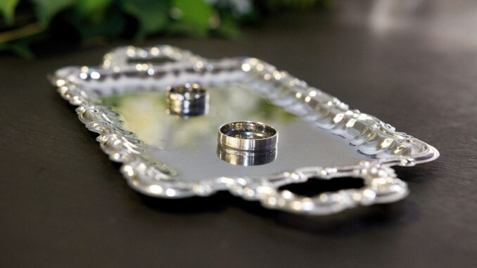Un plateau en argent contenant deux bagues sur une table sombre