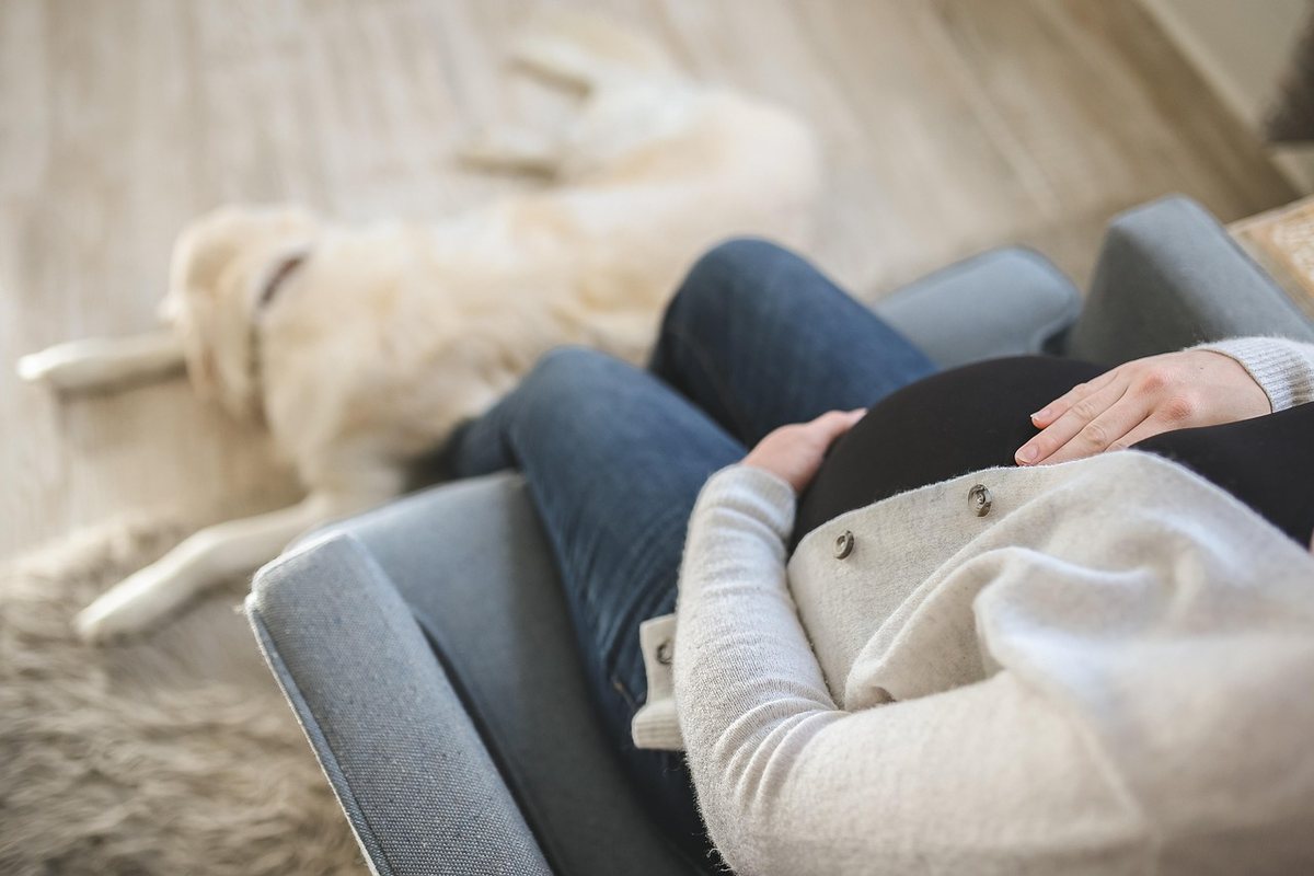 Une femme enceinte repose sur un fauteuil avec son chien