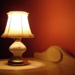 Lampe allumée sur table en bois, éclairage doux contre mur rouge