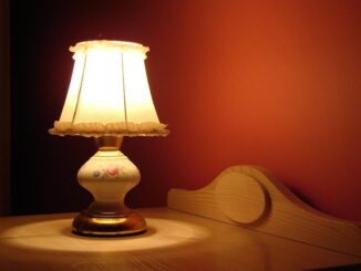 Lampe allumée sur table en bois, éclairage doux contre mur rouge
