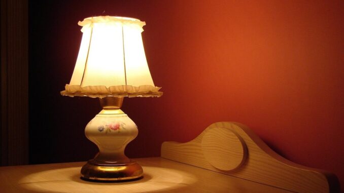 Lampe allumée sur table en bois, éclairage doux contre mur rouge